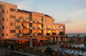a large building with tables and chairs in front of a pool at Capital Coast Resort And Spa in Paphos