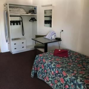 a bedroom with a bed and a desk and a table at Travelway Motel in Port Pirie