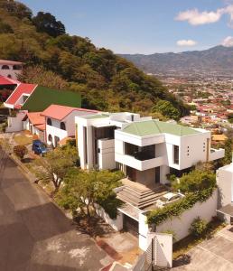 a white building with a green roof on top of a city at Casa Marlui-San José in Curridabat