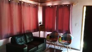 ein Wohnzimmer mit roten Vorhängen, einem Sofa und Stühlen in der Unterkunft Casa La Norma in Nueva Palmira