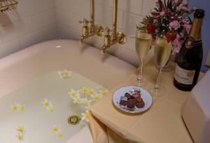 a bath tub with a plate of food and two glasses of champagne at Maddies of Bolwarra in Maitland