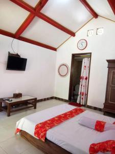 a bedroom with a large bed and a tv in it at Villa Rikna in Watukarung