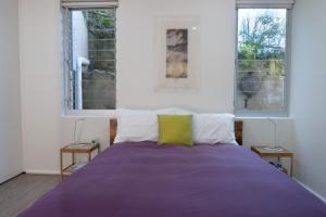 um quarto com uma cama roxa e 2 janelas em Bondi Lock-Down Retreat, The Cute Place To Put Up Your Feet em Sidney