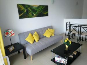 uma sala de estar com um sofá cinzento e almofadas amarelas em Apartamento Green Park Relax em San Miguel de Abona