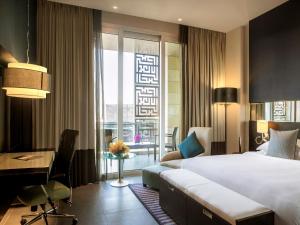 a hotel room with a bed and a desk and a bed and a window at The Boulevard Arjaan by Rotana in Amman