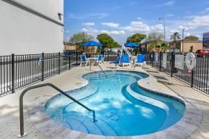 タンパにあるSleep Inn & Suites Tampa Southの青い椅子とフェンス付きの小さなスイミングプール