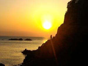 una persona in piedi su un muro che guarda il tramonto di Echizen Guesthouse TAMADA a Fukui