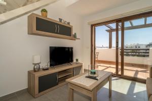 Una sala de estar con un televisor de pantalla plana y una mesa. en Piña, en San Juan de los Terreros