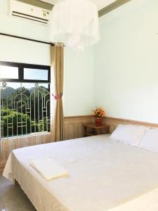 a bedroom with a white bed with a window at Trang Vu Homestay Cu Lao Cham in Tân Hiệp