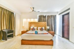 a bedroom with a large bed and a chair at FabHotel Prime Sage in New Delhi