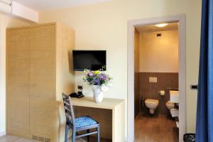 a bathroom with a toilet and a vase of flowers on a desk at Eco Hotel Bonapace in Nago-Torbole