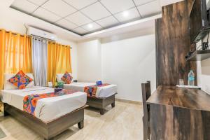 two beds in a room with orange curtains at FabHotel Oakwey Inn - Indiranagar in Bengaluru