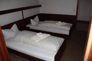 two beds in a room with white sheets and towels at Einfelder Hof garni in Neumünster