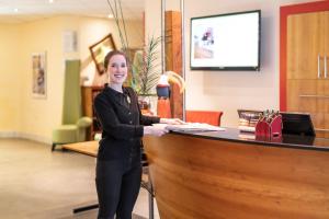 een vrouw die naast een receptie staat bij Anders Hotel Walsrode in Walsrode