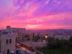 een zonsondergang boven een stad met gebouwen en auto's bij Bunksurfing Hostel in Bethlehem