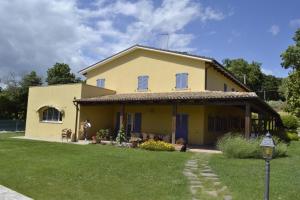 a large yellow house with a grass yard at La Tenuta Del Giglio in Tavullia