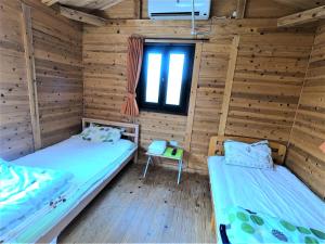 two beds in a room with wooden walls and a window at Koinami in Shima