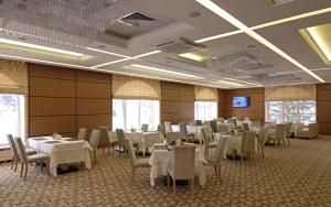 une salle de banquet avec des tables, des chaises et une télévision dans l'établissement Admiral Hotel, à Saransk