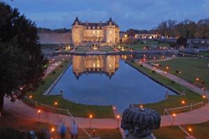 a castle with a lake in front of it at night at ibis Saintes in Saintes