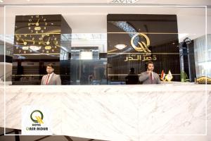Qasr AlDur Hotel في النجف: رجلان في بدلتين يقفان خلف مكتب في متجر