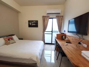台東市的住宿－愛町堡民宿，一间卧室配有一张床和一张书桌及一台平面电视