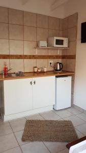 a kitchen with white cabinets and a microwave on the wall at AKKERHUIS GASTEHUIS in Bloemfontein