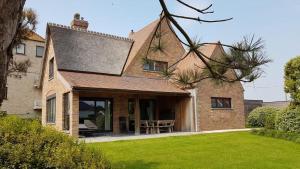 a brick house with a patio and a lawn at Villa Brion**** in Wenduine