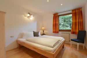 - une chambre avec un lit, une chaise et une fenêtre dans l'établissement Haus Alpenrose, à Scheffau am Wilden Kaiser