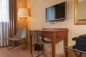 a hotel room with a desk and a television on the wall at Hotel Maggior Consiglio in Treviso