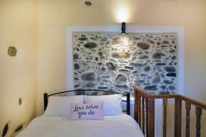 ein Schlafzimmer mit einem Bett mit einer Steinwand in der Unterkunft George & Helen's House in Ayiá + 21 Fotos