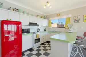 a red refrigerator in a white kitchen with a counter at Pacific Pines Unit 6 in Narooma