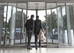 two men in suits walking into a glass building at Hotel Maggior Consiglio in Treviso