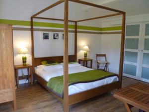 a bedroom with a canopy bed with a green blanket at La Balangere in Coulon