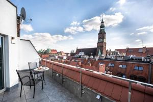 a balcony with a table and chairs and a clock tower at Aparthotel New Lux in Wrocław