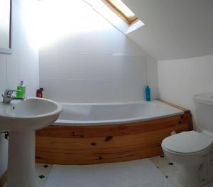 a bathroom with a wooden bath tub next to a toilet at tranquil apartment near Kenmare in Lomanagh
