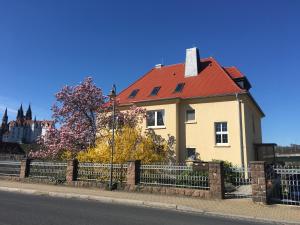 a yellow house with a red roof and a fence at Ferienwohnung „Lena“ in Meißen
