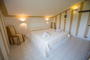 1 dormitorio con 1 cama blanca y 1 silla en Casa Hermosa, en Cefalú