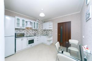 eine Küche mit weißen Schränken sowie einem Tisch und Stühlen in der Unterkunft Видовая квартира Yaroslavichi-2 in Wyschhorod