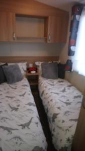 Un dormitorio con 2 camas y una sábana con pescado. en Flamingo land le maple grove caravan hire en Kirby Misperton