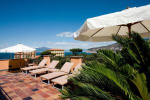 een groep stoelen en een parasol op een patio bij Hotel Palazzo Guardati in Sorrento