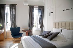 a bedroom with a bed with a blue chair and windows at Four Streets Athens - Luxury Suites Apartments in Athens in Athens