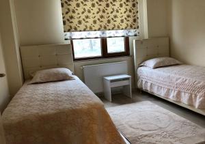 two beds in a small room with a window at Rahal Beşyıldız Apart in Trabzon