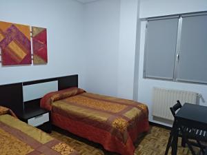 a bedroom with two beds and a table and a window at Apartamento Cigüeña in Logroño