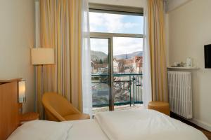 a hotel room with a bed and a large window at Grand Hôtel Filippo Strasbourg Nord in Niederbronn-les-Bains