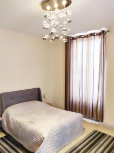 1 dormitorio con cama y lámpara de araña en Chez Fanny - appartement de qualité hypercentre Cahors, en Cahors