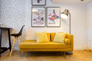 ein gelbes Sofa im Wohnzimmer mit Bildern an der Wand in der Unterkunft Leah Studios in Budapest