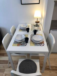 mesa de comedor blanca con sillas y lámpara en CR Przytulny Apartament przy Pałacu Branickich, en Białystok