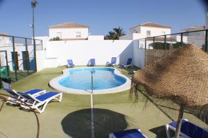 una piscina con sillas y sombrillas en un patio en Apartamentos La Palmera, en Conil de la Frontera