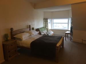 a bedroom with a bed and a chair and a window at Camelot Seafront Hotel in Blackpool