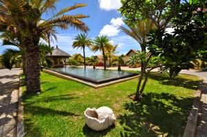 einen Pool in einem Garten mit Palmen in der Unterkunft Oasis Villas by Fine & Country in Grand Baie